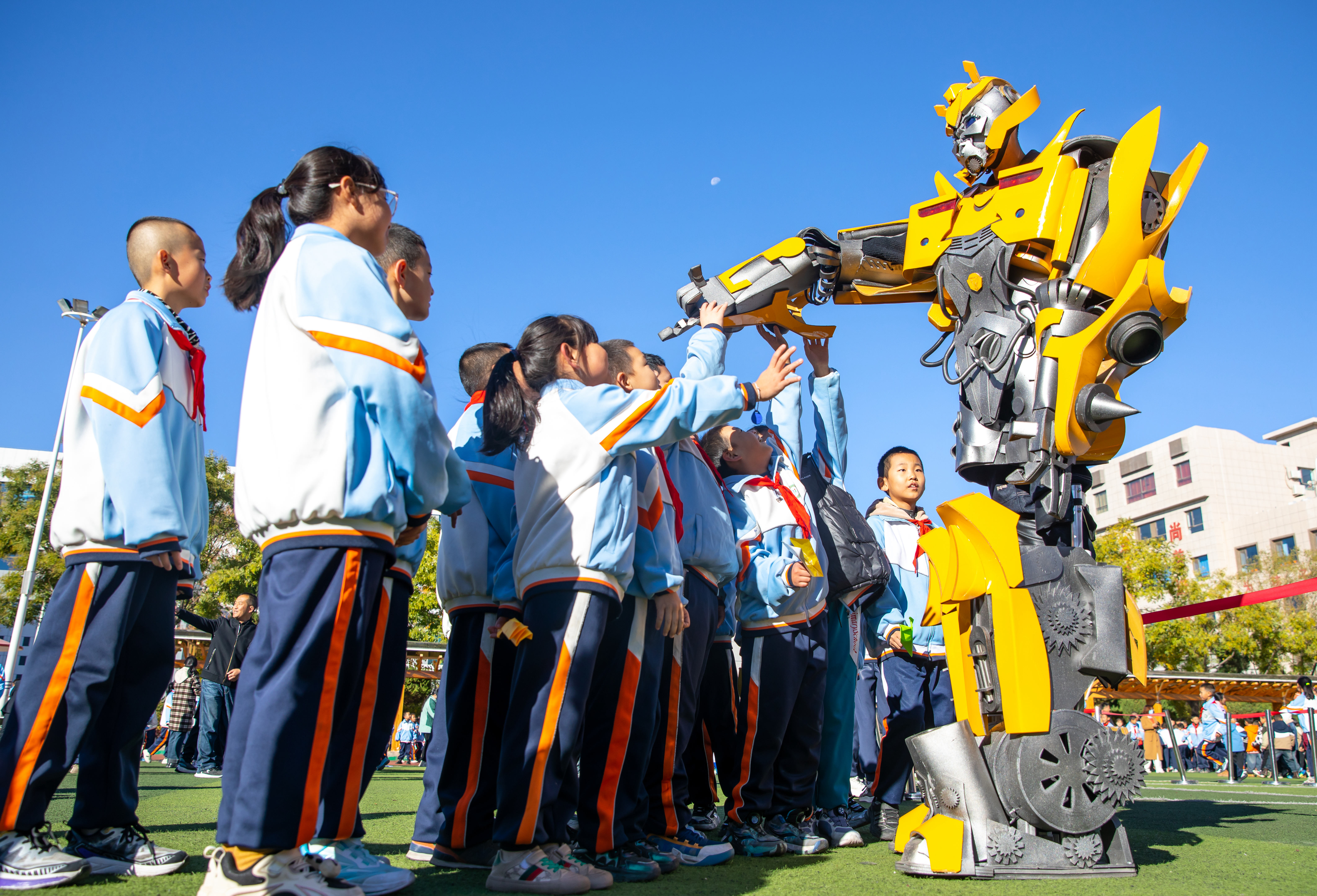 2024年10月22日，在甘肅省張掖市甘州區(qū)北街街小學(xué)科技大篷車嘉年華活動上，學(xué)生與“大黃蜂”機(jī)器人互動。楊瀟 攝.jpg