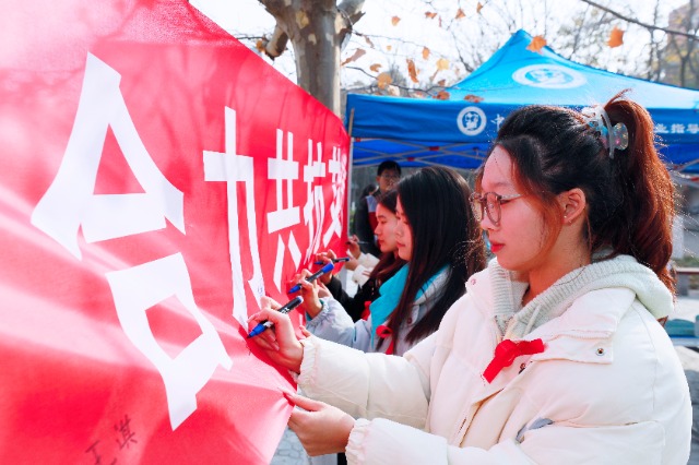 20231127中國石油大學(xué)（華東）青年學(xué)子在合力共抗艾滋的條幅上簽字，表達(dá)抗擊艾滋病的決心和信心  .jpg