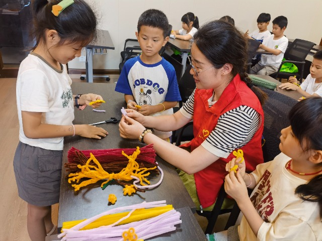 7月12日，在泰州市海陵區(qū)城東街道林湖社區(qū)，泰州市大浦小學(xué)“綠葉”暑期公益班的老師正在教孩子們一起做手工2（拍攝者：泰州市大浦中心小學(xué)  陳惠婷）.jpg