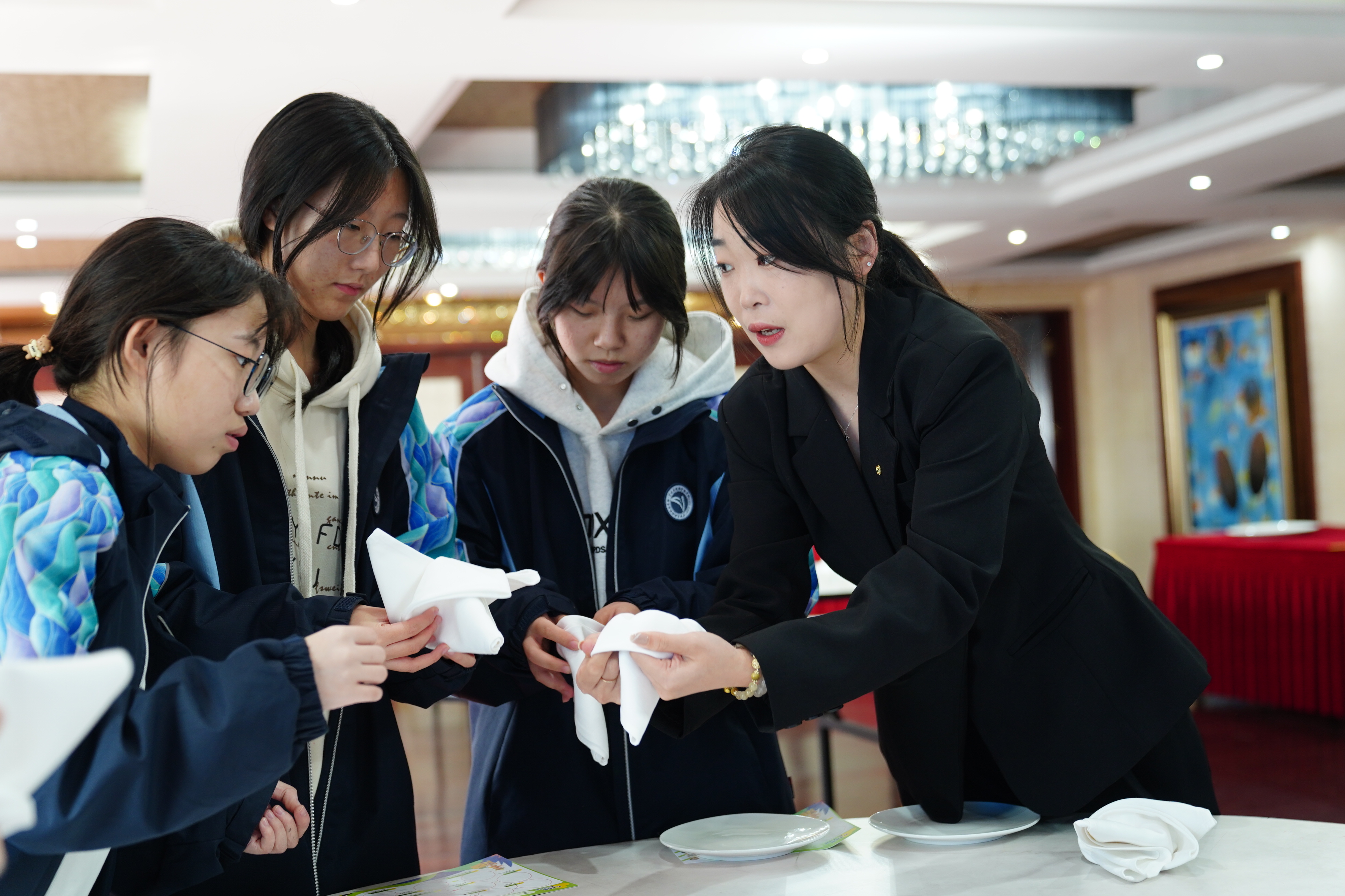 寧波東錢(qián)湖旅游學(xué)校學(xué)生在企業(yè)導(dǎo)師（右一）的指導(dǎo)下體驗(yàn)指尖藝術(shù)(中餐擺臺(tái))項(xiàng)目 胡佳 攝.jpg