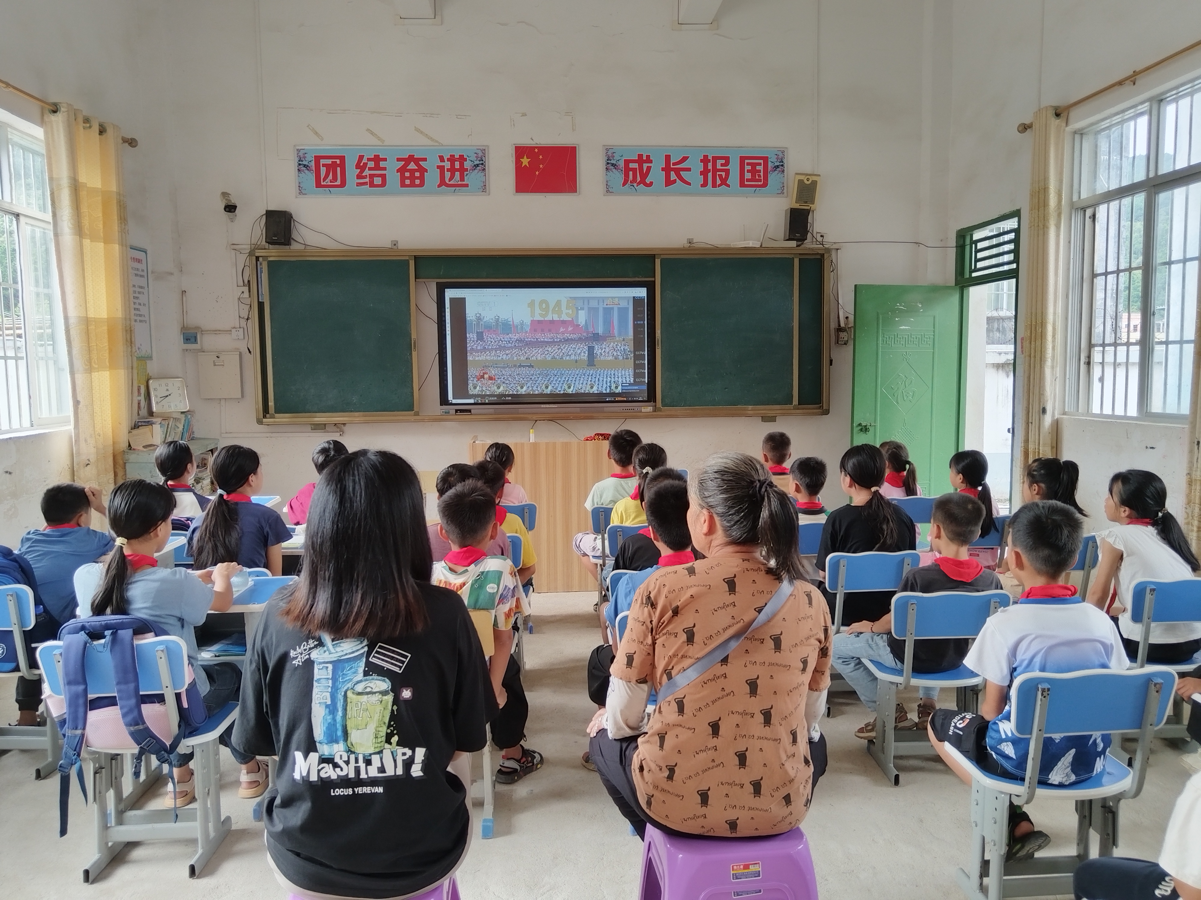 欽北區(qū)板城鎮(zhèn)高龍小學(xué)家長(zhǎng)和學(xué)生一起觀看閱兵儀式。.jpg
